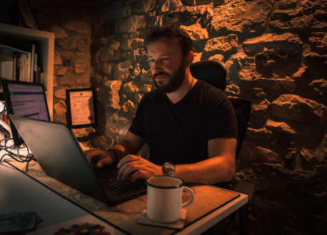 man sitting in a dim room working on his computer